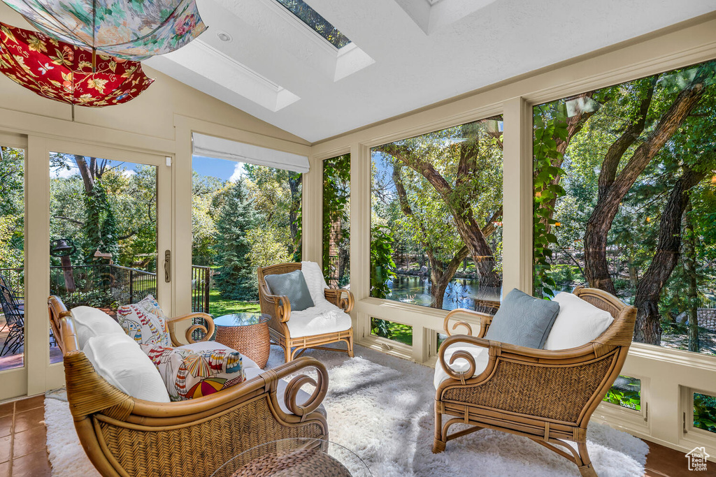 Sunroom / solarium with a skylight, vaulted ceiling, view of scattered trees, and a water view