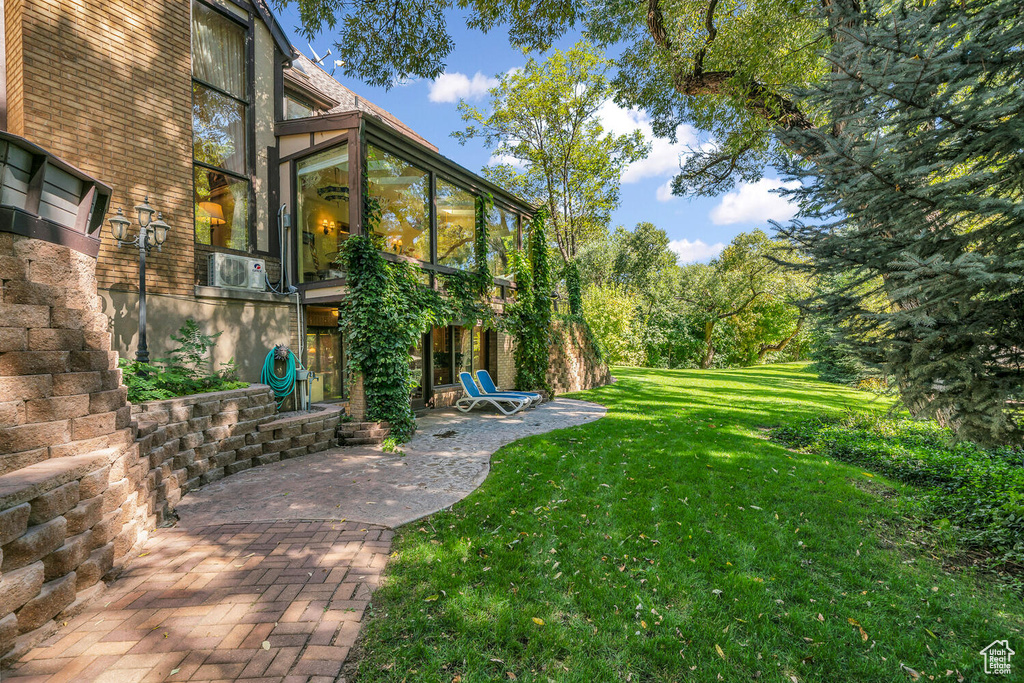 View of grassy yard featuring a patio and a sunroom