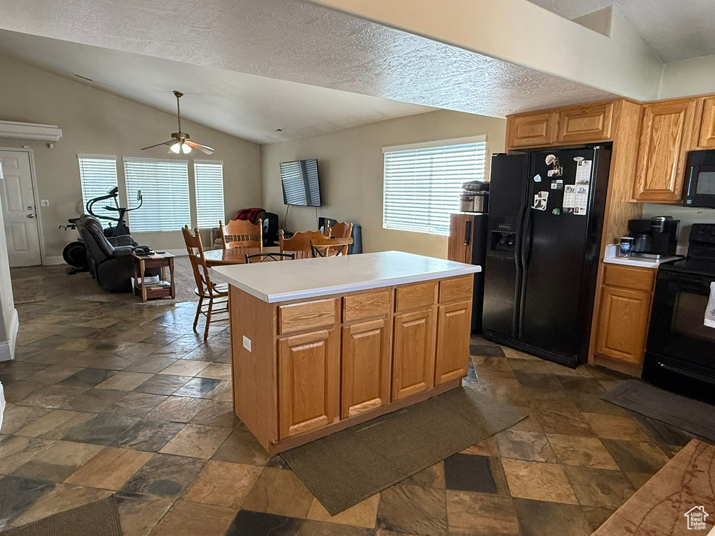 Kitchen with black appliances, vaulted ceiling, dark stone finish flooring, a ceiling fan, and light countertops