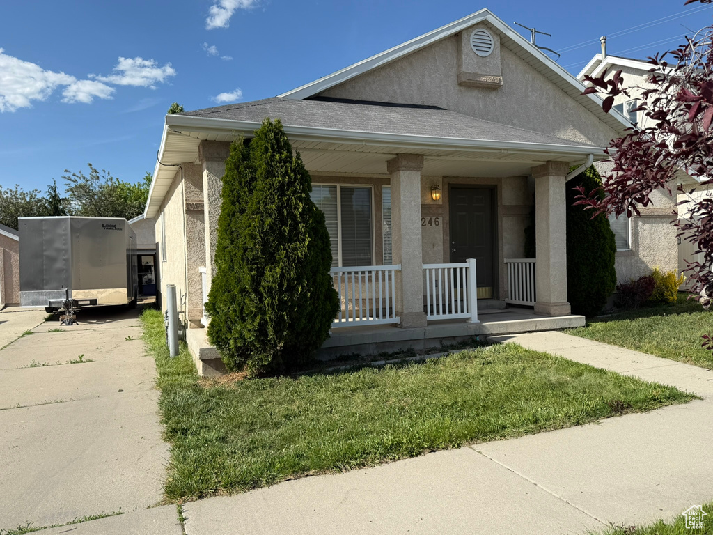 Bungalow featuring a porch, stucco siding, a front lawn, driveway, and a shingled roof
