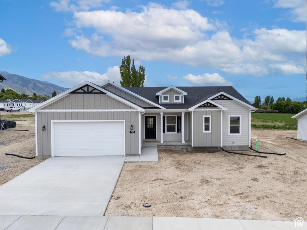 View of front of home featuring board and batten siding, an attached garage, driveway, and a mountain view