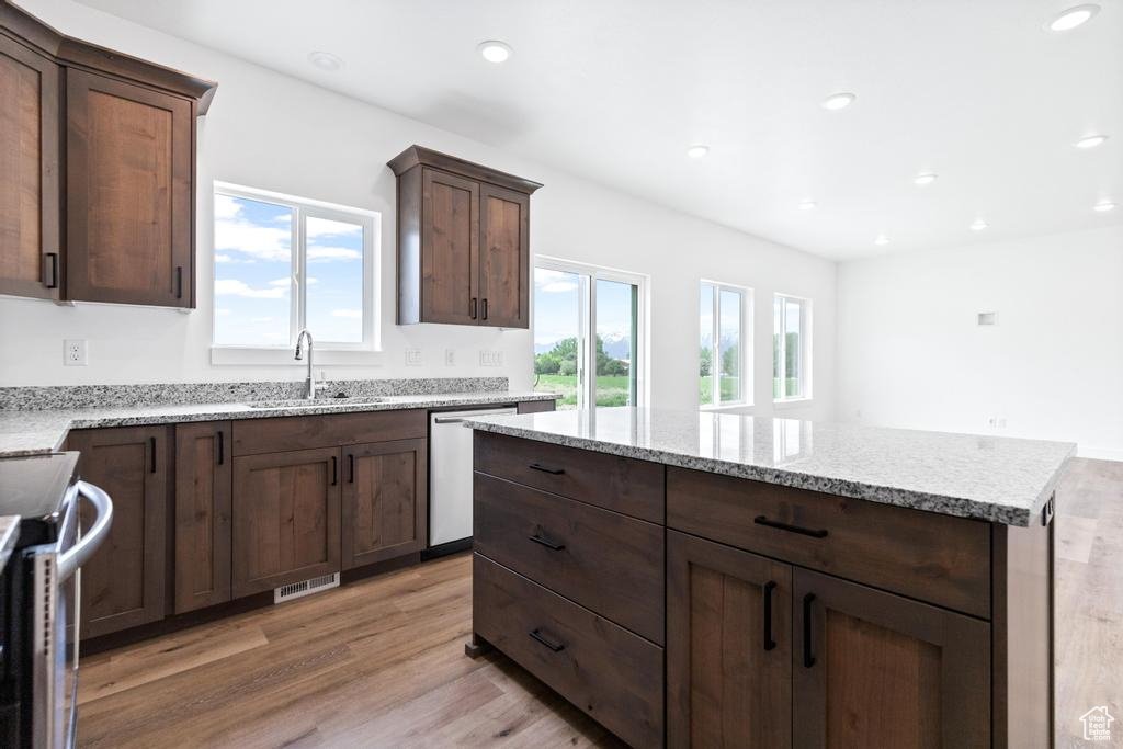 Kitchen with a sink, light wood-type flooring, recessed lighting, light stone counters, and stainless steel appliances