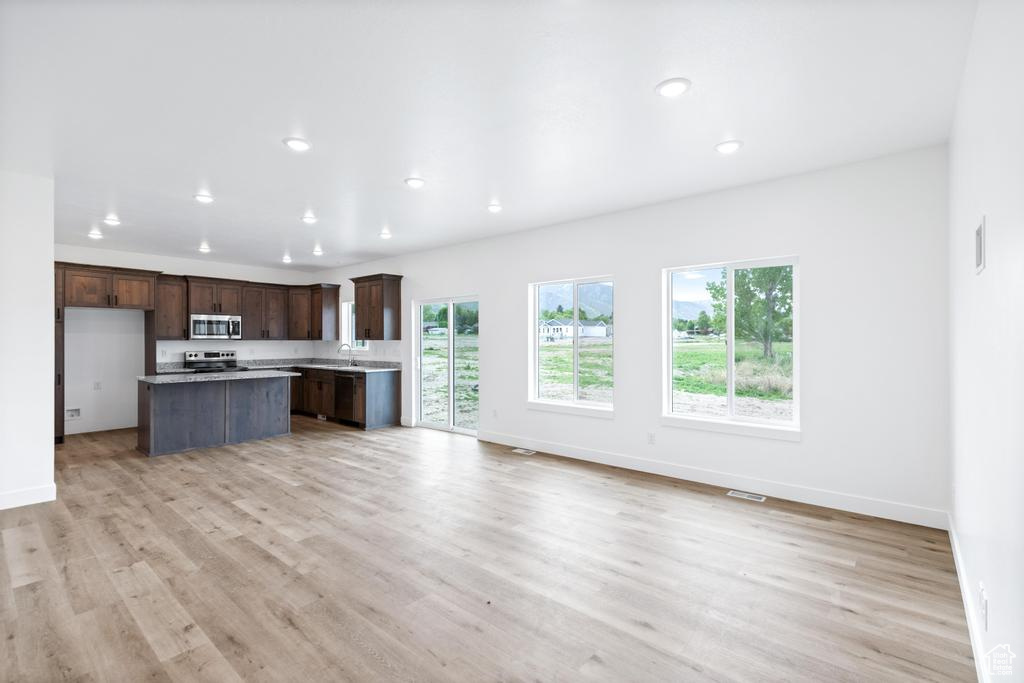 Kitchen with stainless steel appliances, open floor plan, light wood finished floors, and recessed lighting