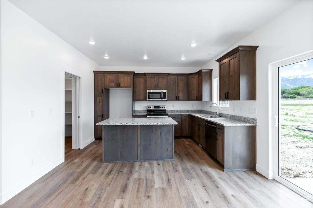 Kitchen featuring stainless steel appliances, a sink, light wood-type flooring, a kitchen island, and recessed lighting