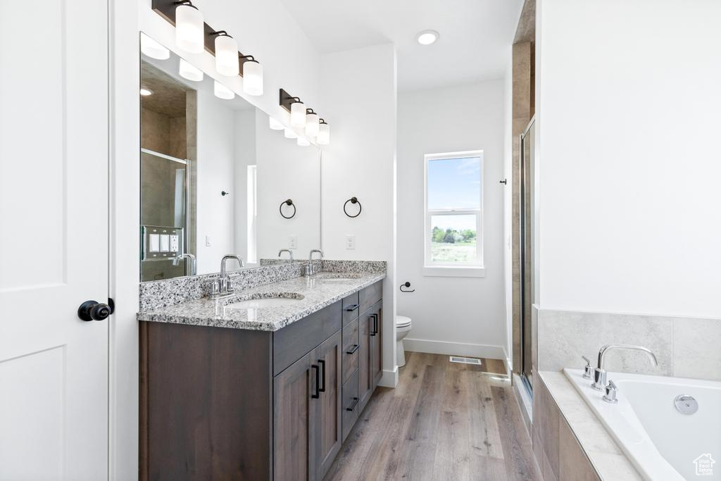 Full bathroom with a stall shower, wood finished floors, double vanity, and a bath