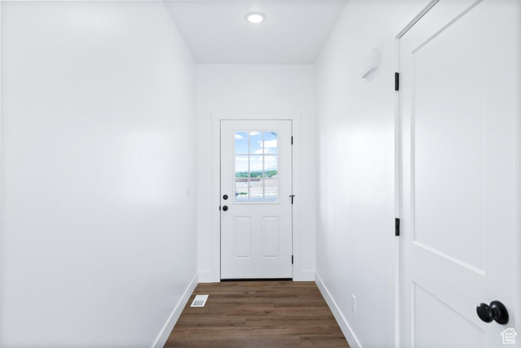 Doorway to outside featuring baseboards and dark wood-style floors