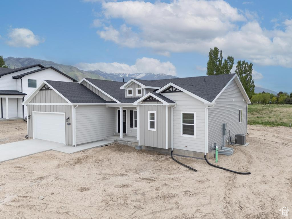 View of front of home featuring board and batten siding, a garage, concrete driveway, a mountain view, and a porch