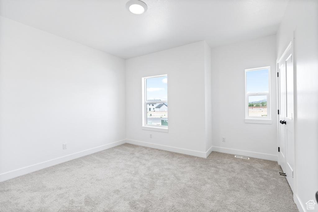 Unfurnished room featuring light carpet and baseboards