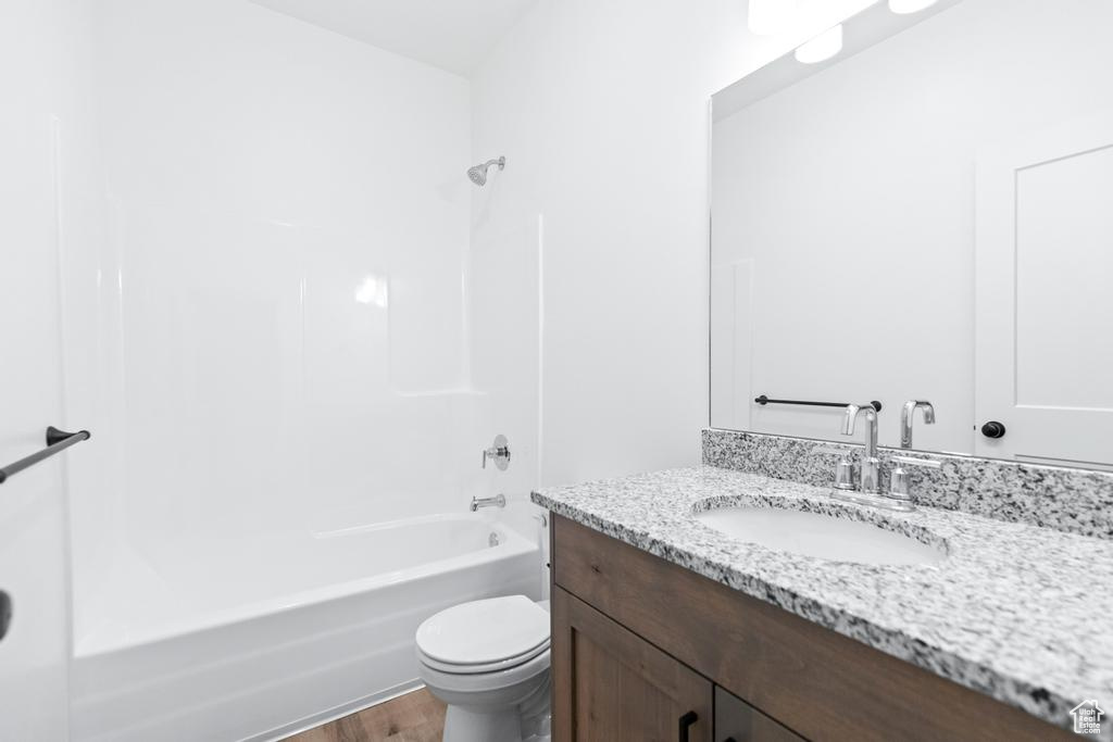 Full bath with toilet, bathing tub / shower combination, wood finished floors, and vanity