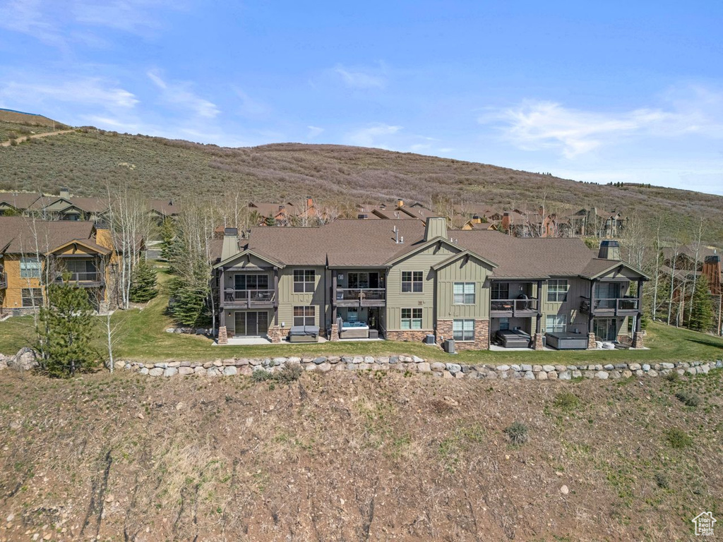 View of front of property with board and batten siding, a chimney, a balcony, and a mountain view
