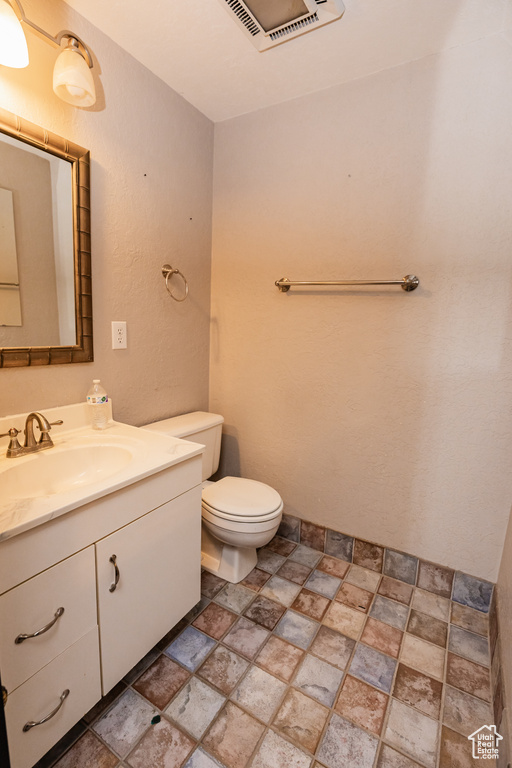 Bathroom with stone finish flooring, toilet, and vanity