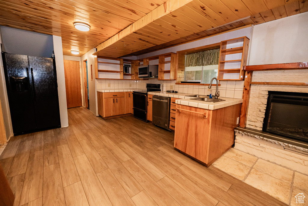 Kitchen featuring a sink, black appliances, open shelves, tile countertops, and wooden ceiling