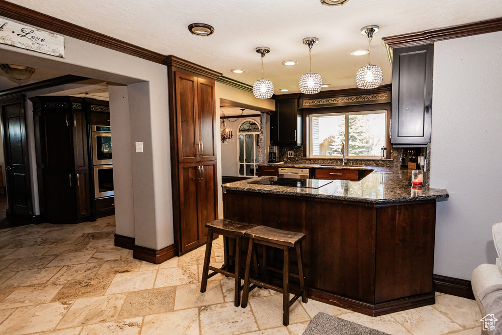 Kitchen with baseboards, double oven, backsplash, a sink, and dark stone countertops