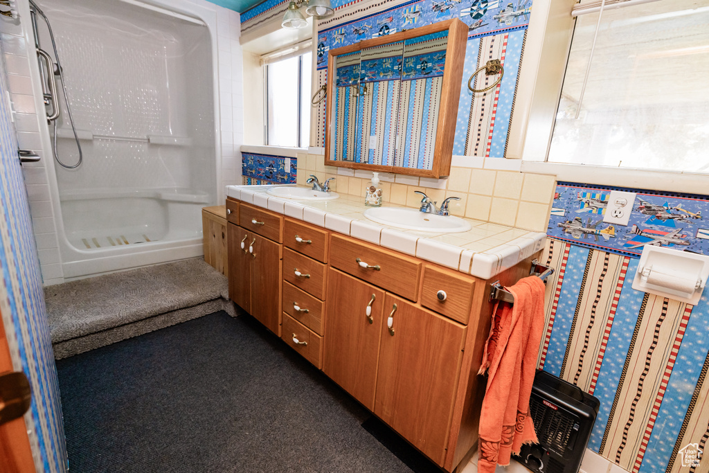 Bathroom featuring a shower stall, backsplash, and double vanity