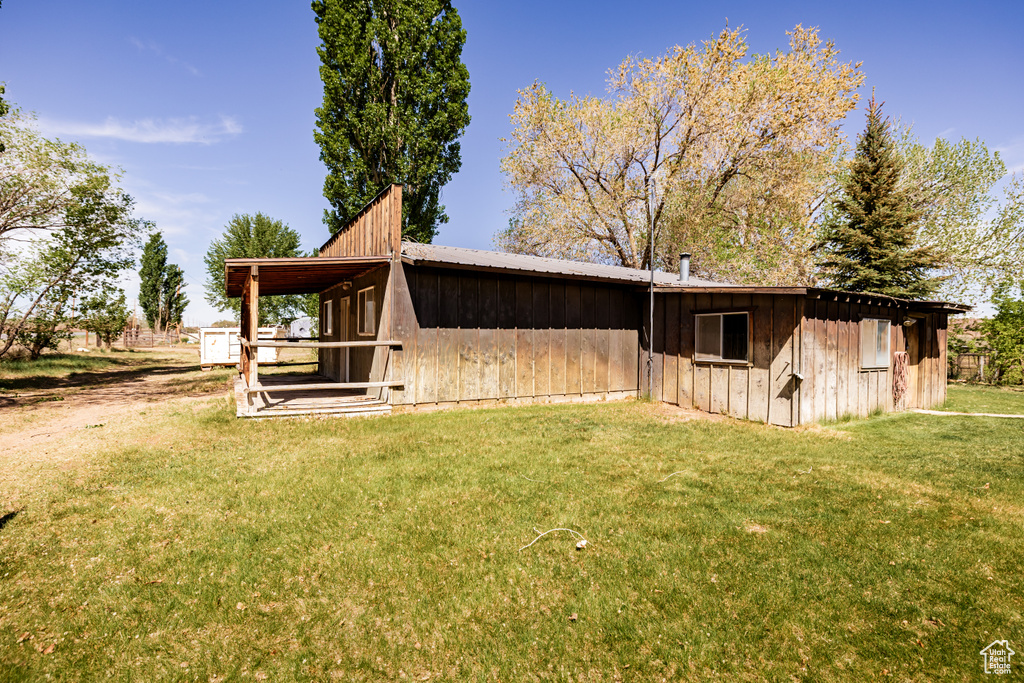 View of side of property with a yard and an outdoor structure