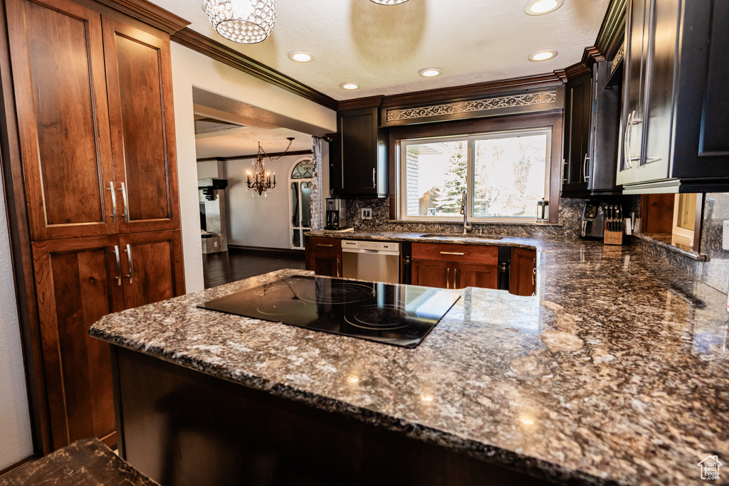 Kitchen with a sink, dishwasher, a chandelier, black electric stovetop, and decorative backsplash