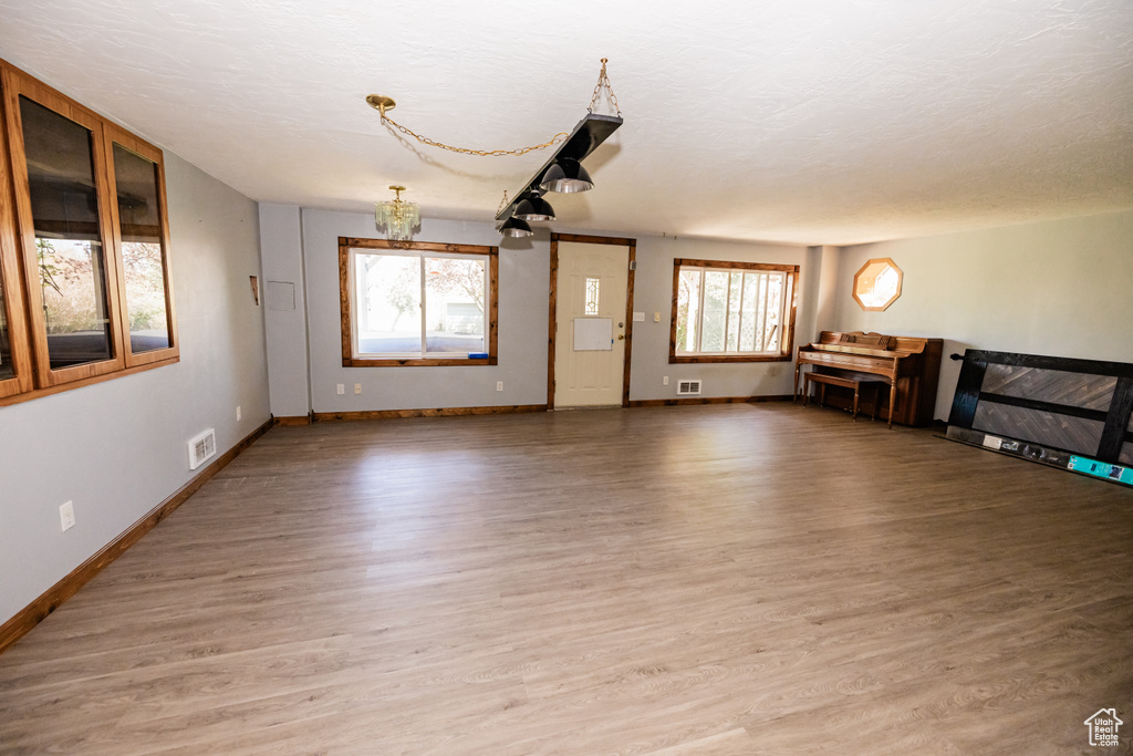Unfurnished living room with baseboards, light wood-style floors, and a chandelier