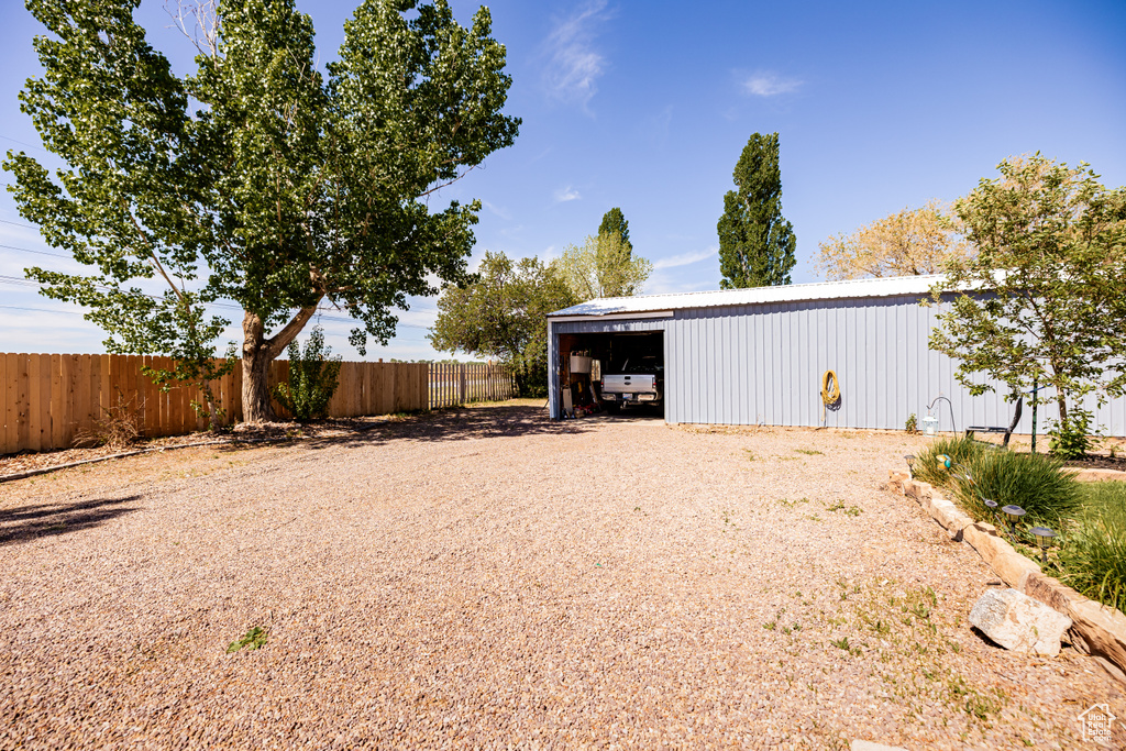 View of yard with fence, a pole building, a detached garage, and an outdoor structure