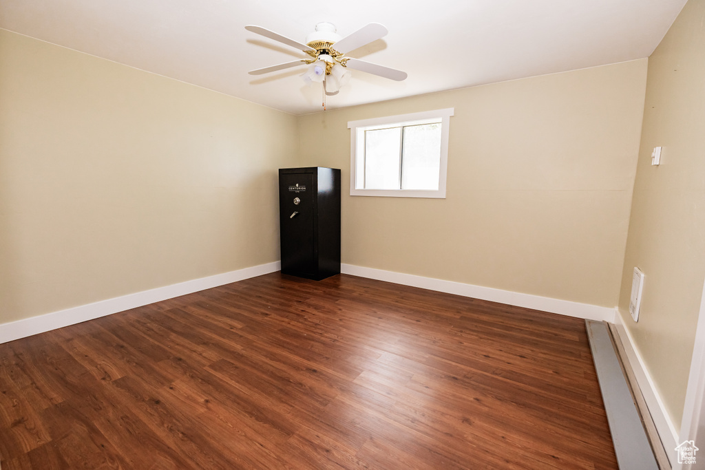 Unfurnished room featuring dark wood finished floors, a ceiling fan, and baseboards