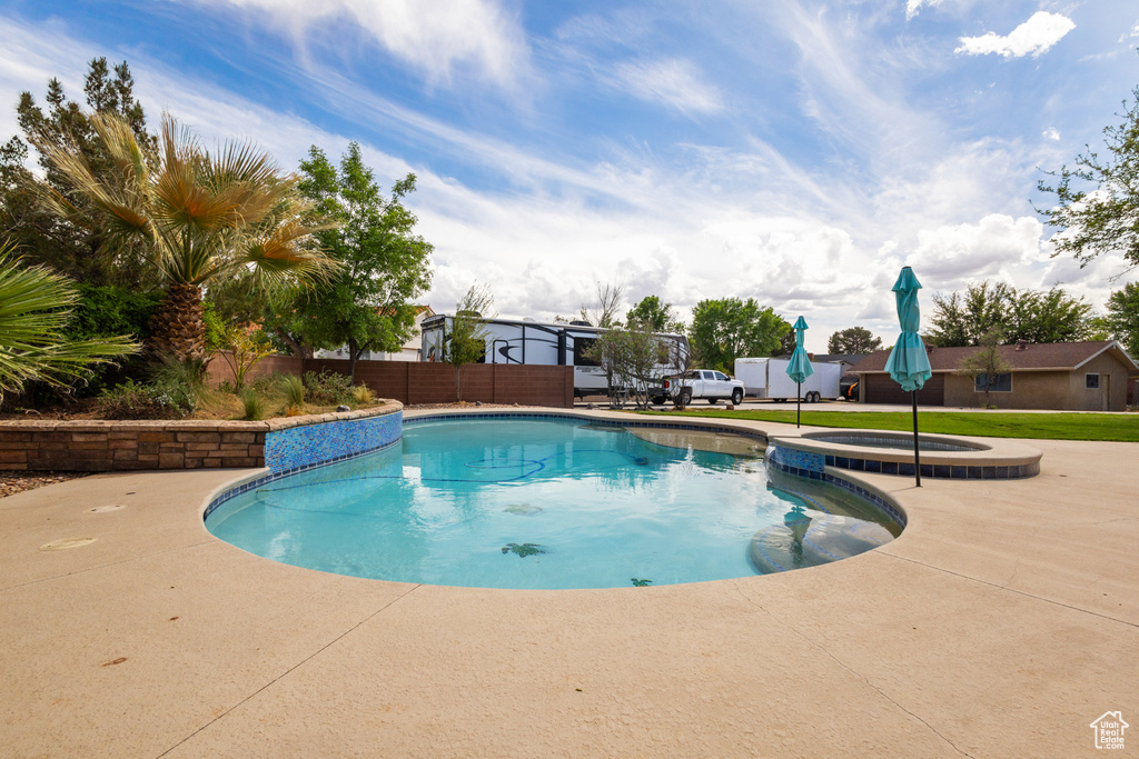 View of pool featuring fence, a patio area, and a pool with connected hot tub