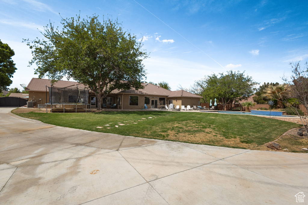 Single story home with a trampoline, a patio area, a pool, and a front lawn