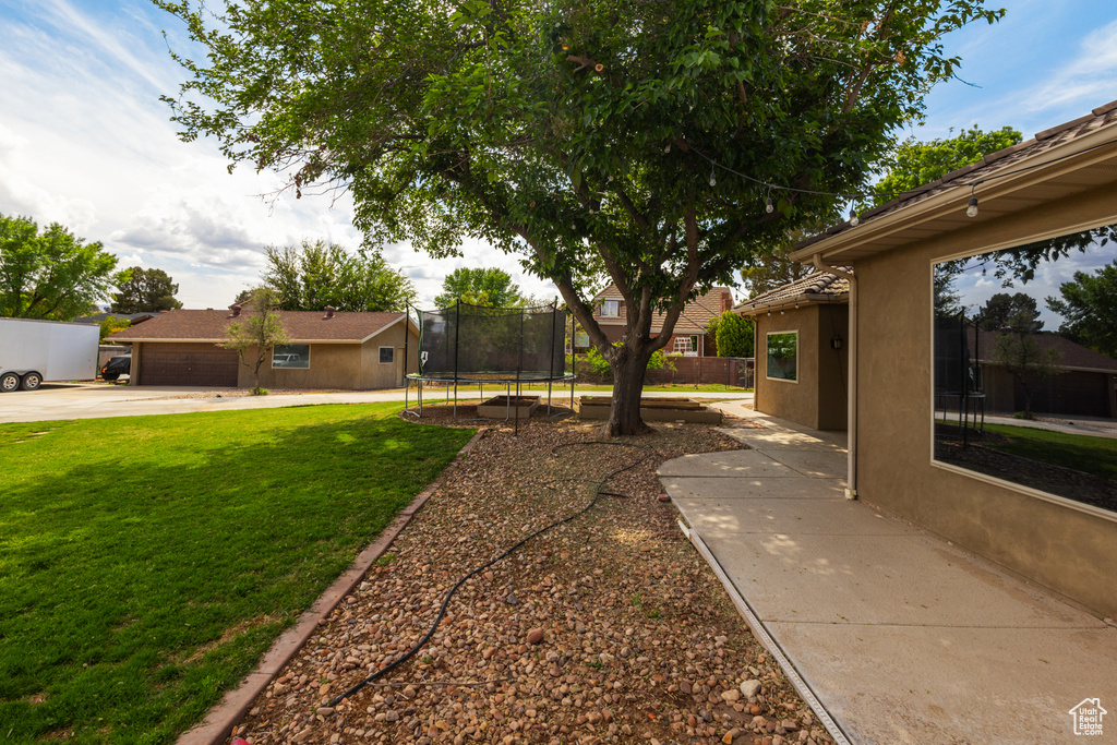 View of yard with a trampoline and concrete driveway