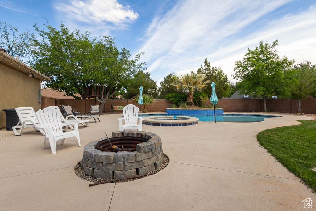 View of pool featuring a fire pit, a fenced backyard, a patio, and a pool with connected hot tub