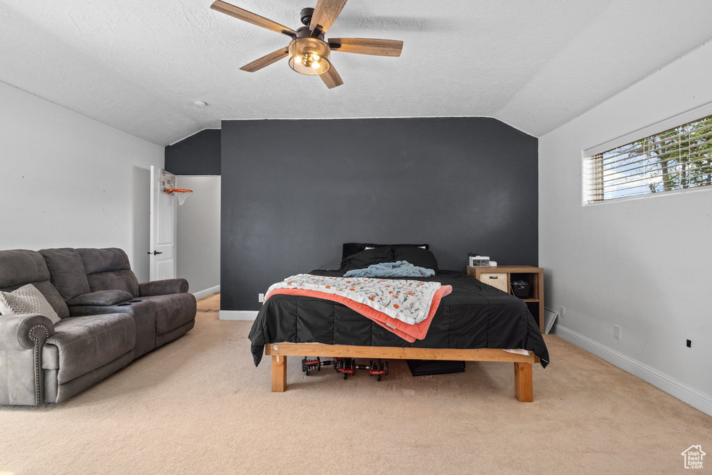 Carpeted bedroom with vaulted ceiling, baseboards, and ceiling fan