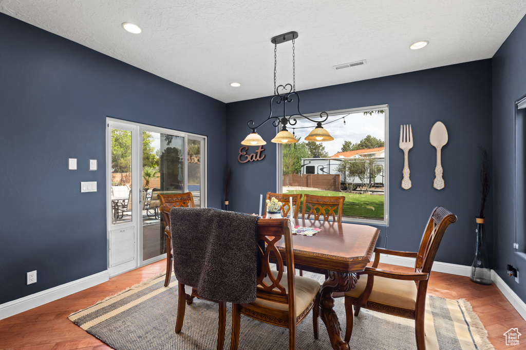 Dining space with baseboards, light wood-style flooring, recessed lighting, and a textured ceiling