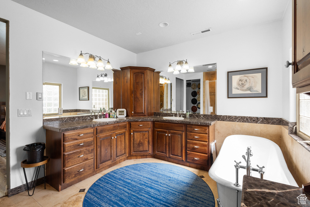 Bathroom featuring a freestanding tub, double vanity, a shower, and tile patterned floors