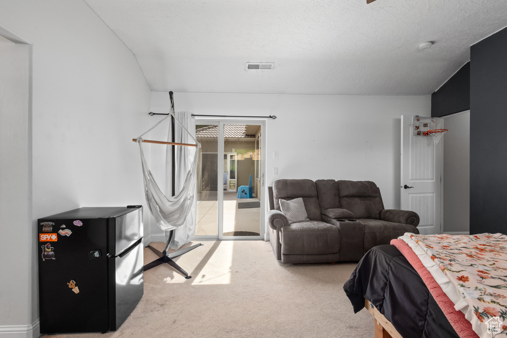 Bedroom with access to outside, carpet floors, and freestanding refrigerator