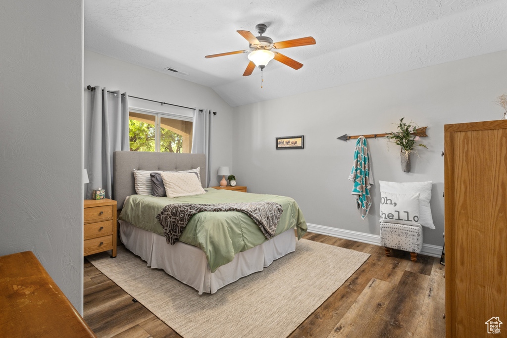 Bedroom with wood finished floors, vaulted ceiling, a ceiling fan, and baseboards
