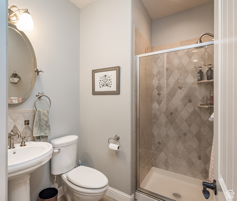 Full bathroom with a stall shower, toilet, baseboards, and a sink