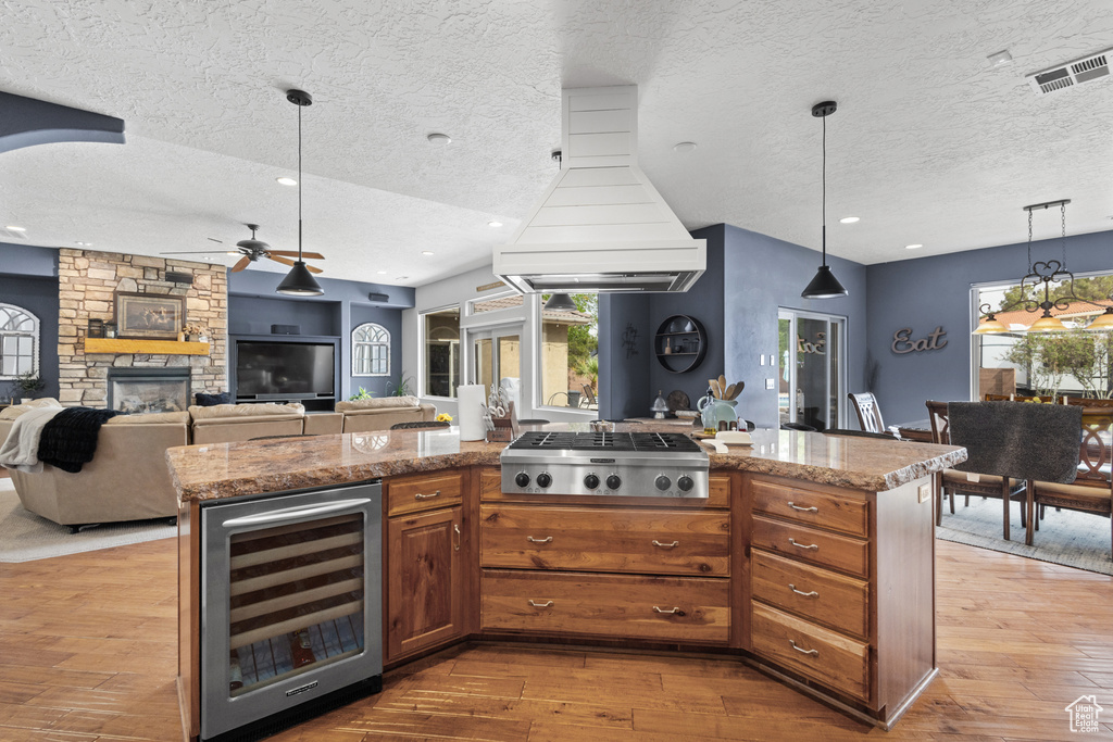 Kitchen featuring wine cooler, stainless steel gas cooktop, ceiling fan, a textured ceiling, and custom range hood