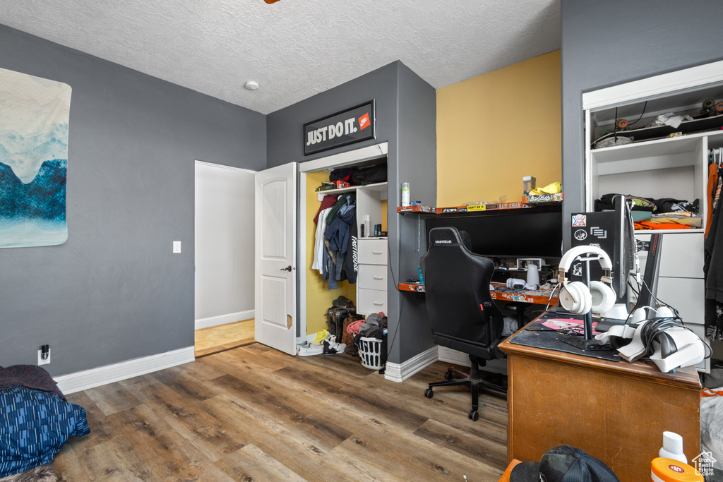 Office area with wood finished floors, baseboards, and a textured ceiling
