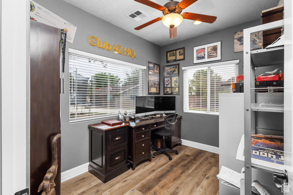 Home office with a ceiling fan, light wood-style flooring, and baseboards