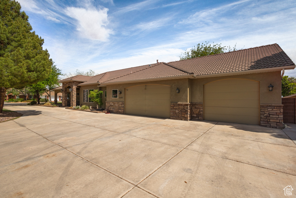 Mediterranean / spanish home with stone siding, stucco siding, driveway, an attached garage, and a tile roof