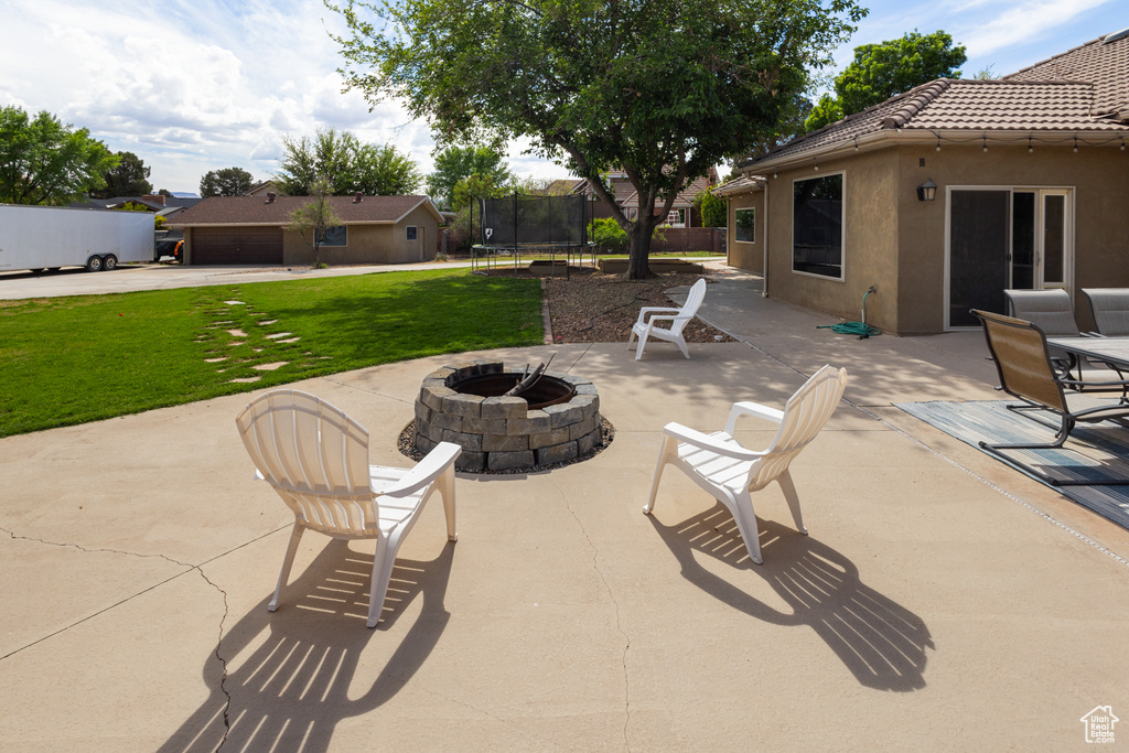 View of patio / terrace featuring an outdoor fire pit and a trampoline