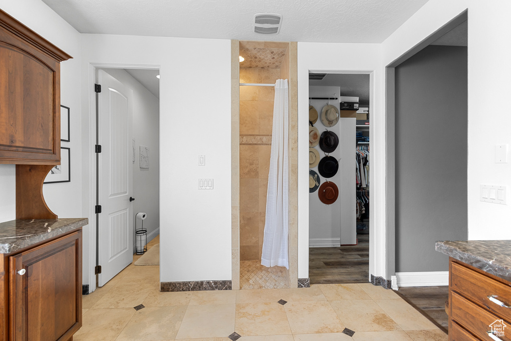 Full bath featuring a stall shower, vanity, a spacious closet, tile patterned floors, and baseboards