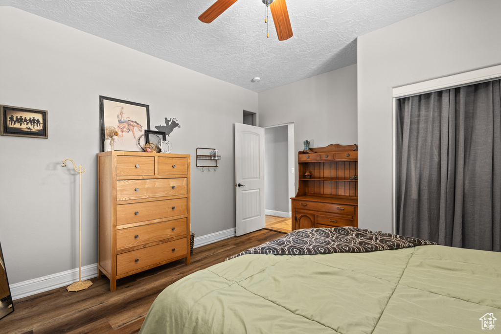 Bedroom featuring baseboards, wood finished floors, a textured ceiling, and ceiling fan