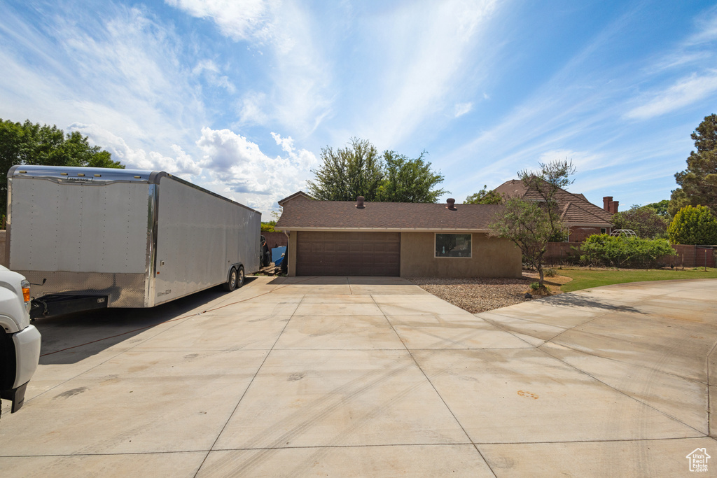 View of front facade featuring driveway, a garage, and fence