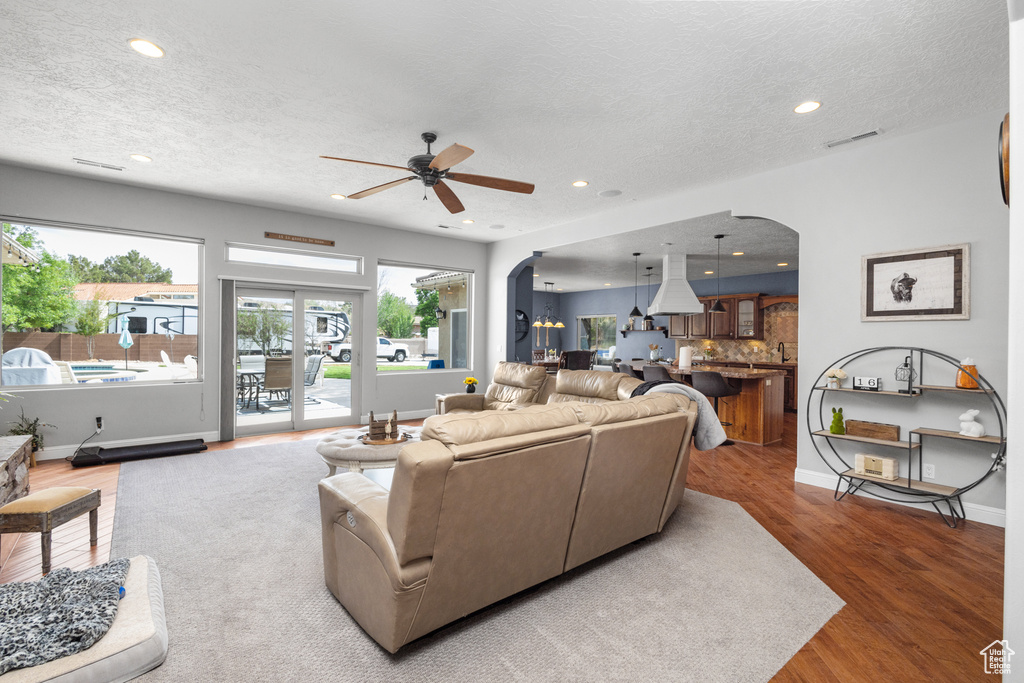 Living room featuring arched walkways, recessed lighting, a textured ceiling, a ceiling fan, and wood finished floors