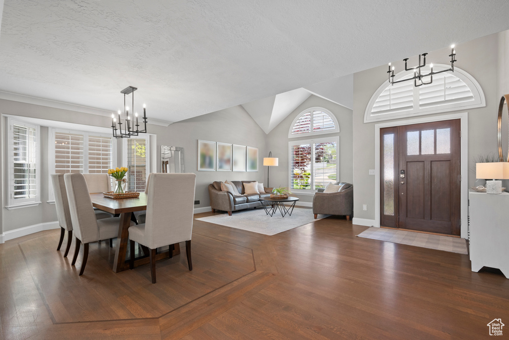 Dining area featuring a chandelier, baseboards, a textured ceiling, and lofted ceiling
