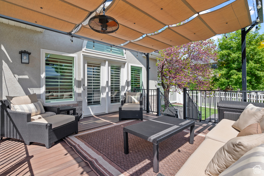 Wooden terrace with an outdoor hangout area, fence, and ceiling fan