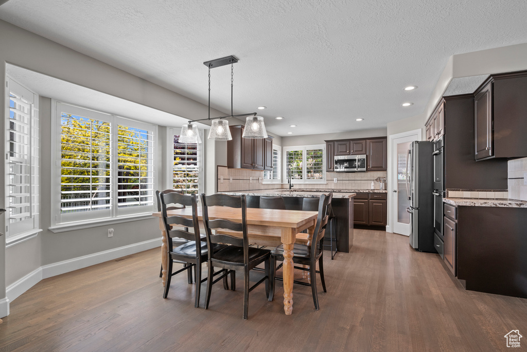 Dining area with light wood-style floors, baseboards, recessed lighting, and a textured ceiling