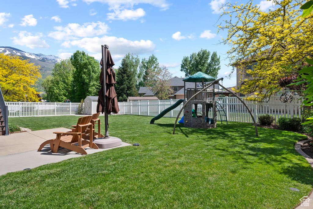 View of yard with a playground, a storage shed, a patio area, an outbuilding, and a mountain view