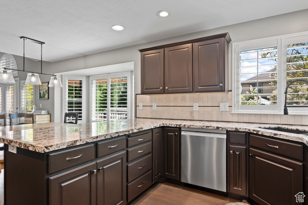 Kitchen with stainless steel dishwasher, a sink, dark brown cabinets, decorative backsplash, and recessed lighting