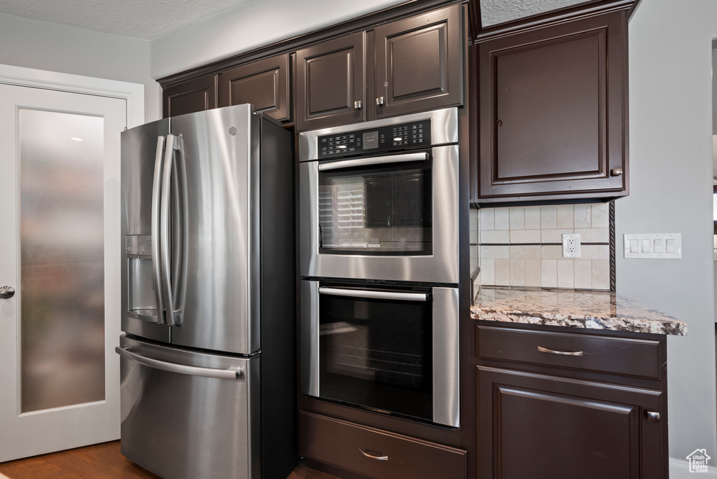 Kitchen with stainless steel appliances, dark brown cabinets, and decorative backsplash
