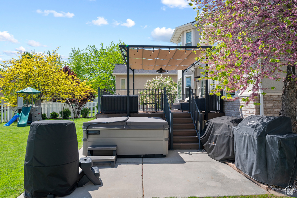 View of patio / terrace featuring a hot tub, a playground, a deck, grilling area, and a pergola