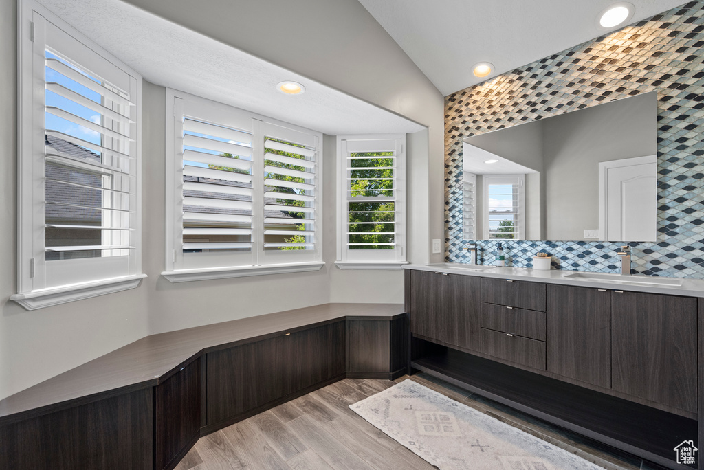 Full bathroom with wood finished floors, double vanity, recessed lighting, tasteful backsplash, and lofted ceiling
